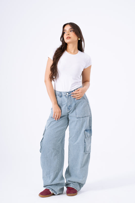 Woman wearing light blue cargo pants and a white t-shirt on a white background