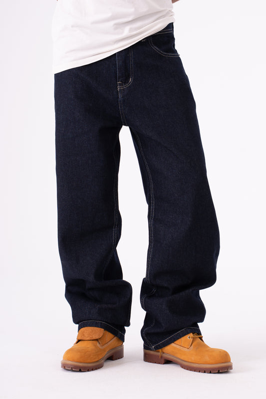 Person wearing dark blue baggy jeans on a white background