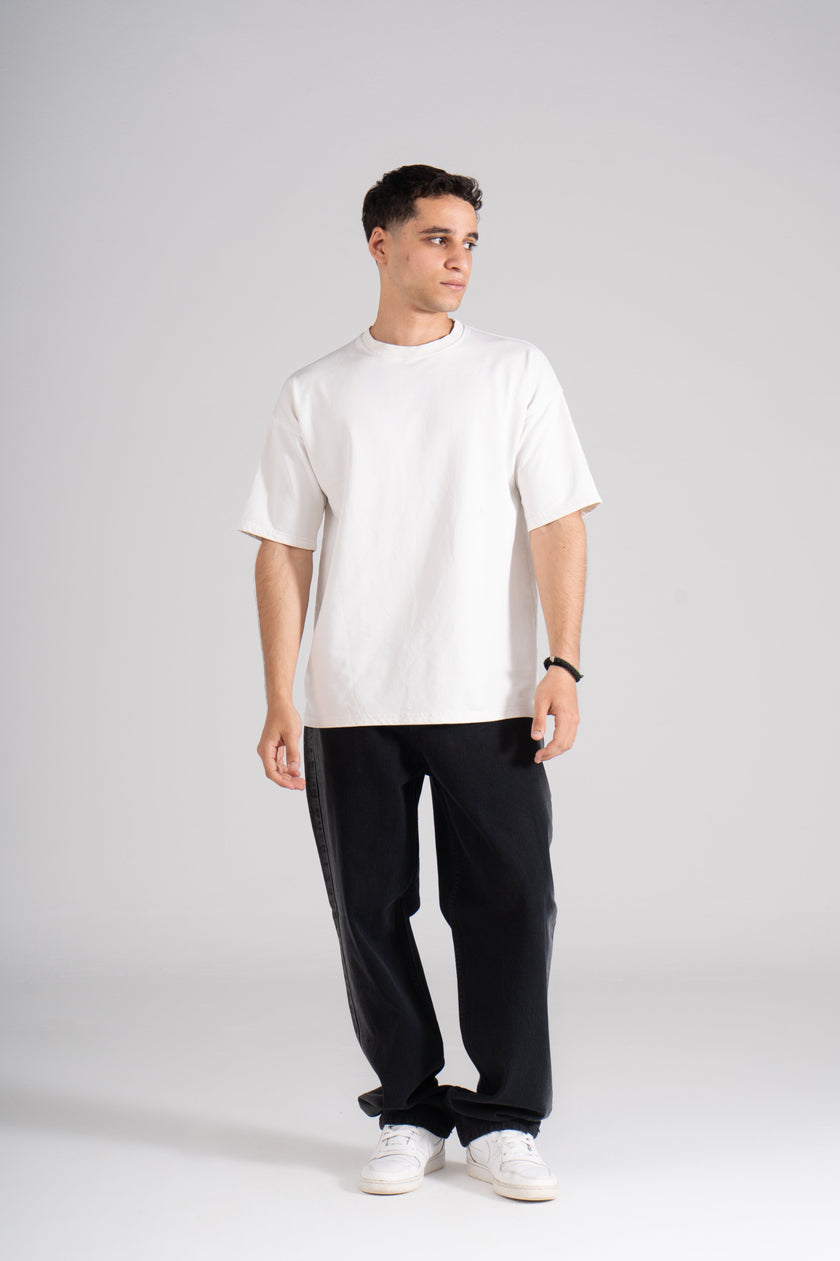  A man dressed in a white t-shirt paired with stylish black denim pants.