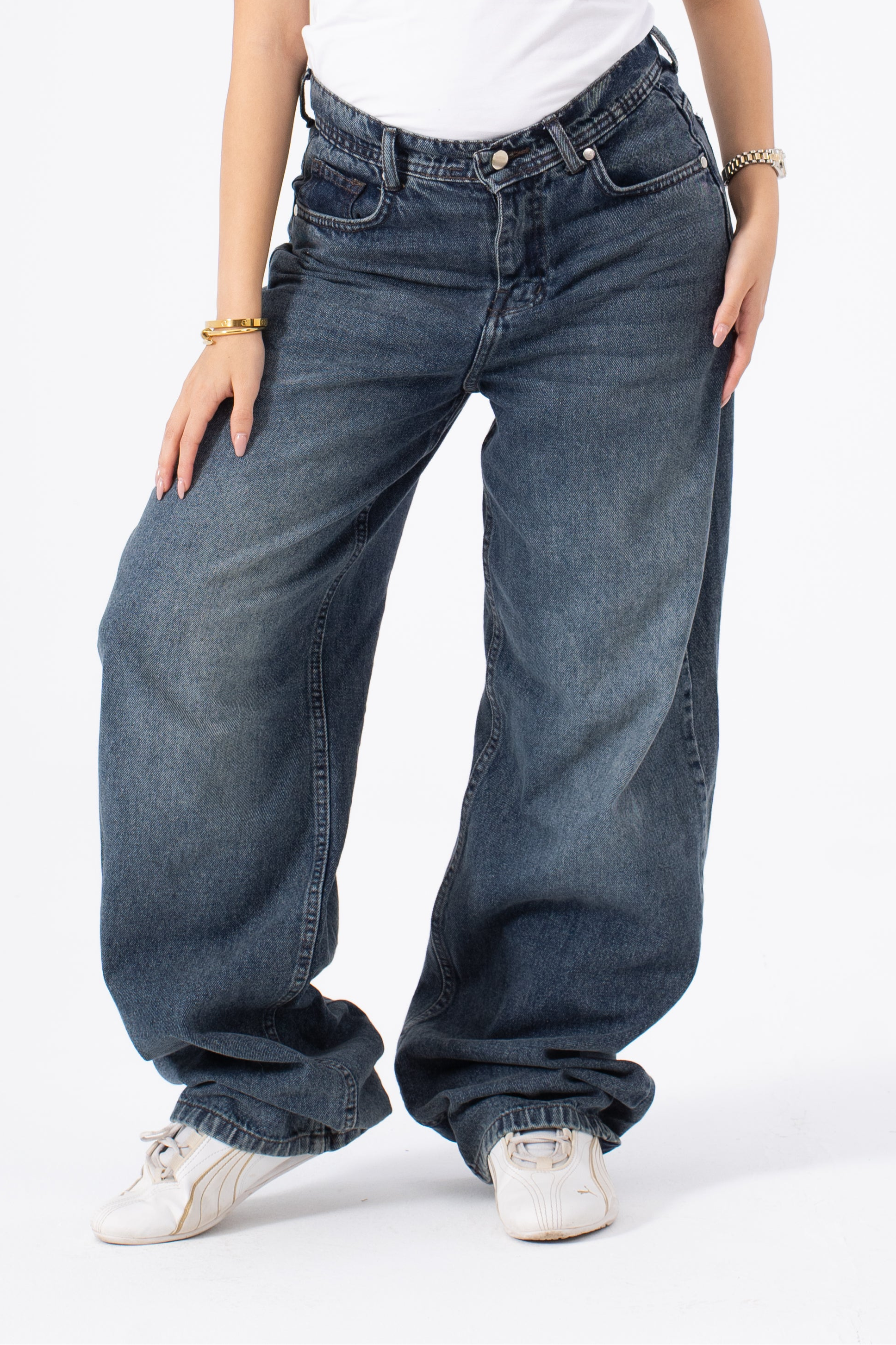 Person wearing blue baggy jeans on a white background