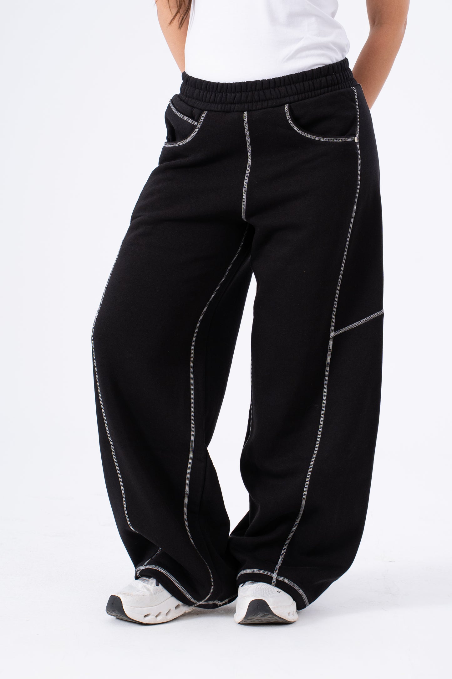 Black pants with white piping worn by a person on a white background