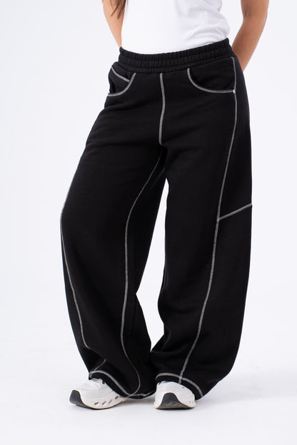 Black pants with white piping worn by a person on a white background