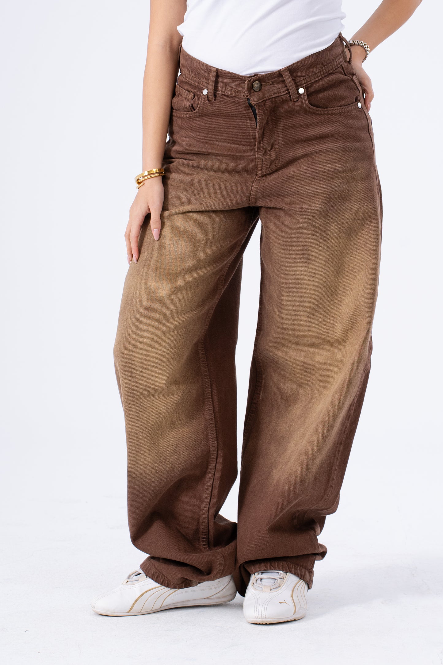 Brown baggy jeans worn by a person on a white background