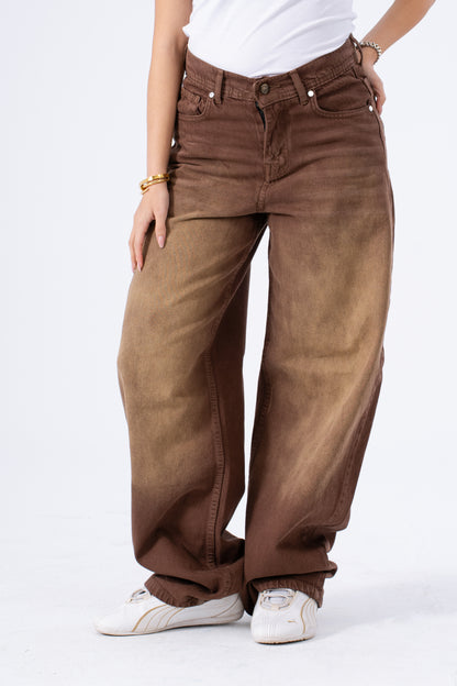 Brown baggy jeans worn by a person on a white background